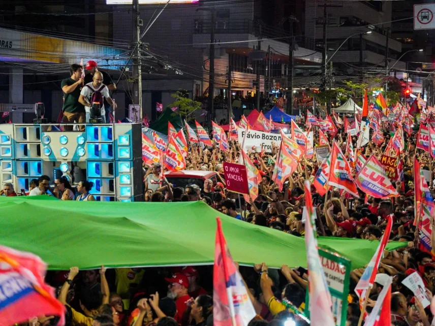 Multidão reunida em ato político com bandeiras do Brasil e cores do PT em Fortaleza.