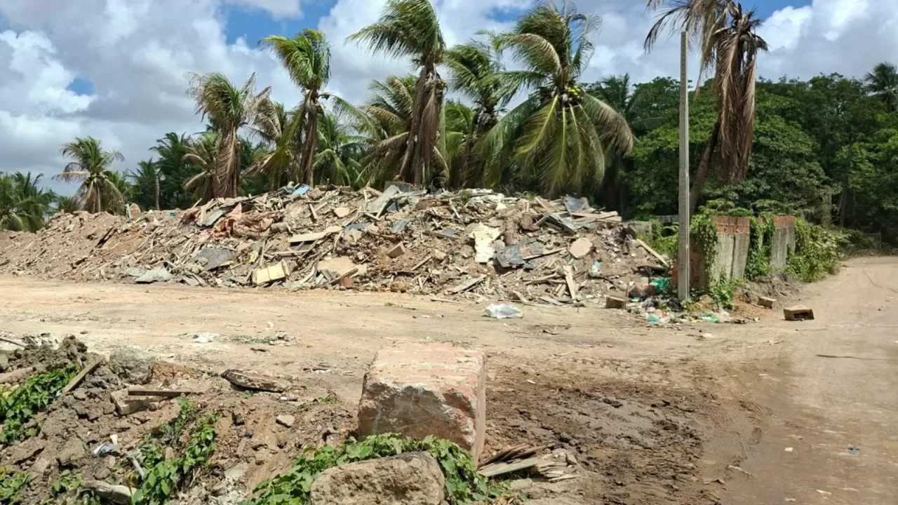 Terreno no Jangurussu com acúmulo de terra e resíduos de construção próximo a curso d'água.