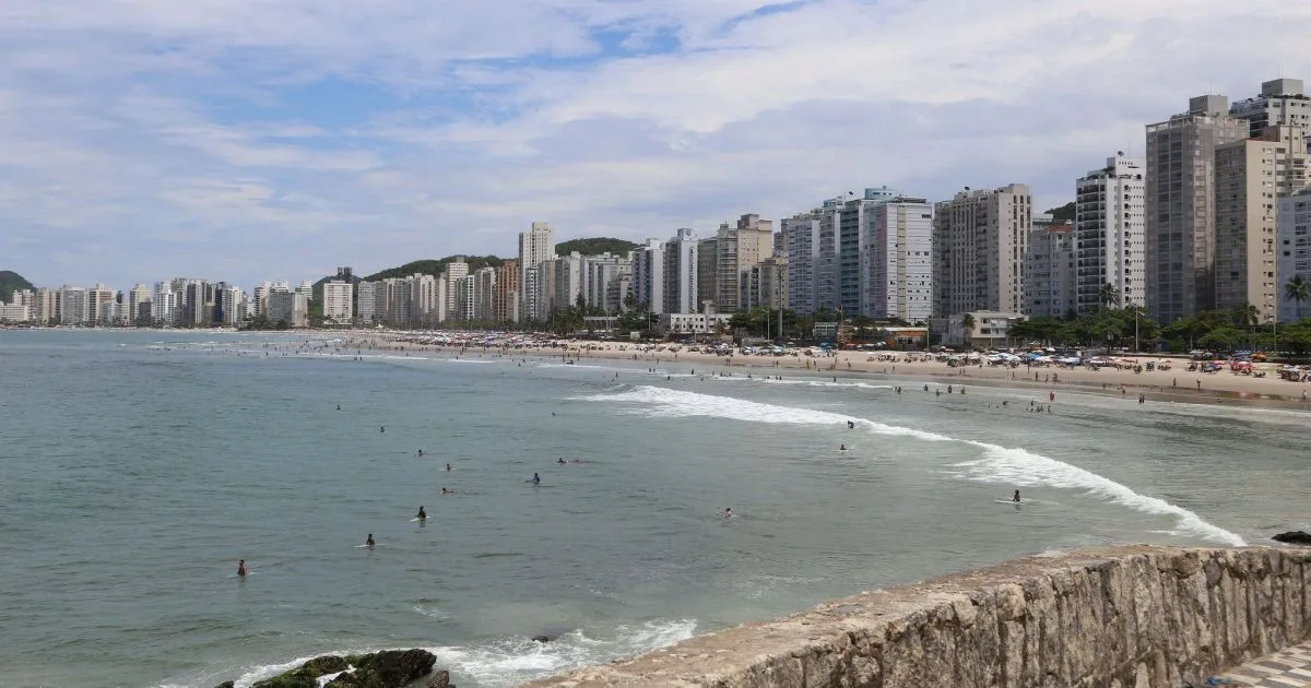 Vista aérea de uma praia brasileira com área urbana ao fundo.